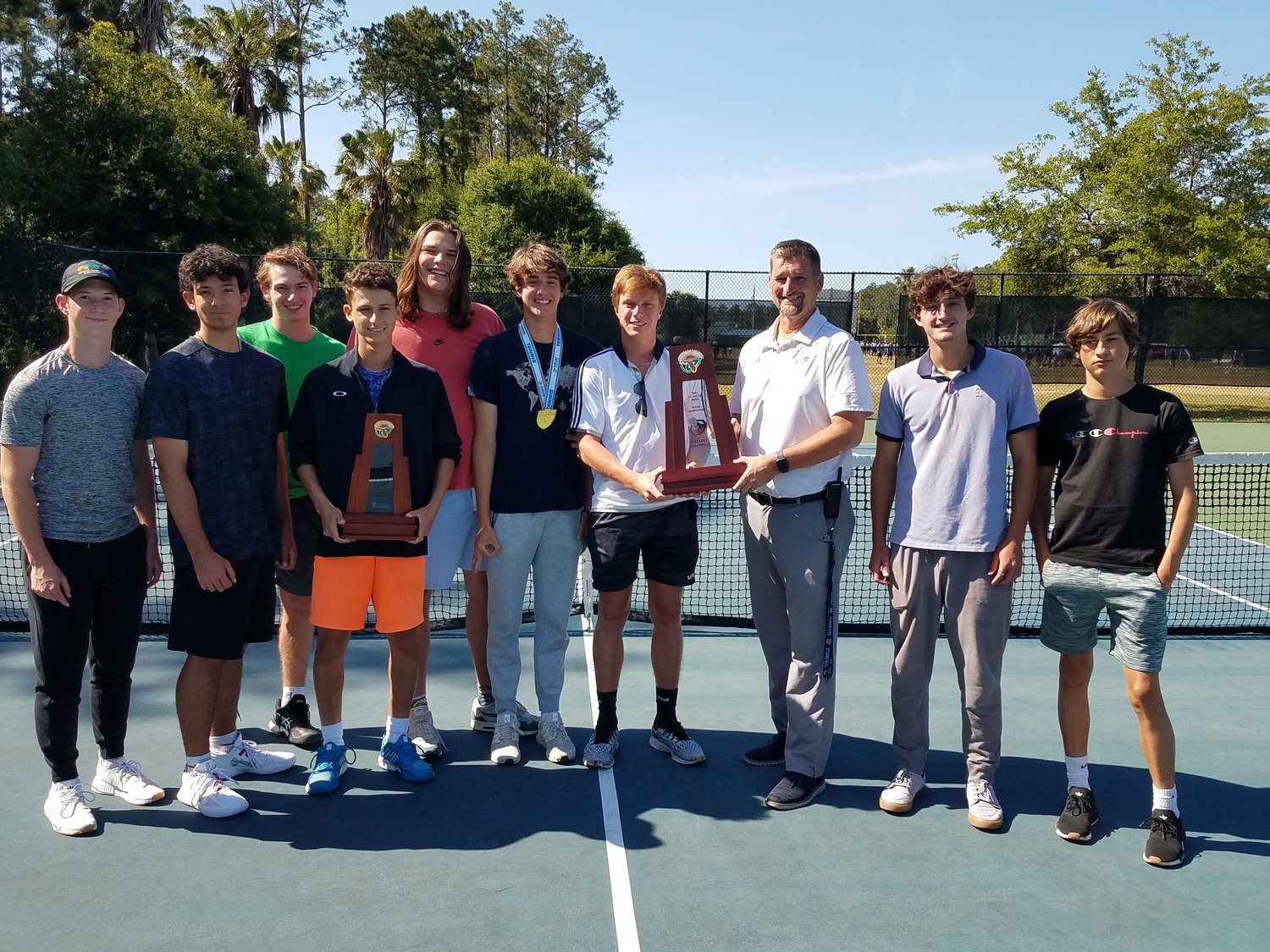 Adam Logan and the rest of the Ponte Vedra High boys tennis team present athletic director Michael Harrison with the Class 3A state championship trophy May 2. Read the story inside on page 29.